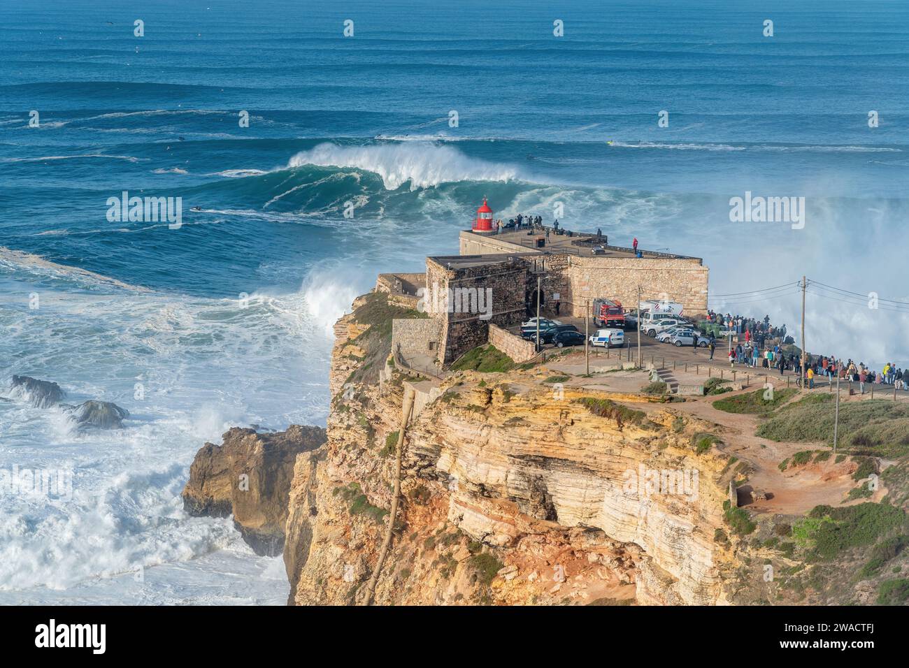Onde che si infrangono vicino al forte di Sao Miguel Arcanjo Lighthouse a Nazare, Portogallo, famoso per i surfisti per avere le onde più grandi del mondo. Foto Stock