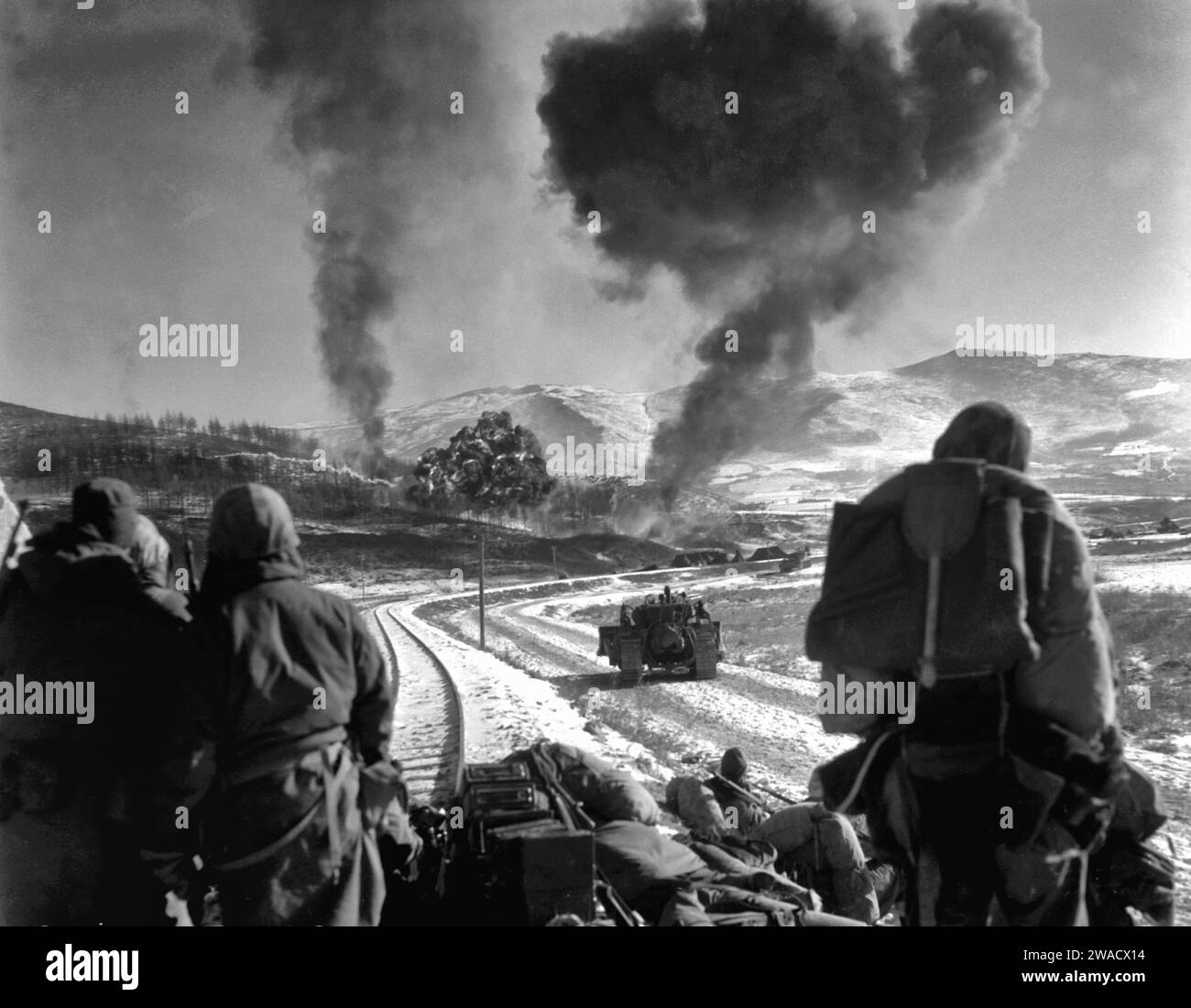 I Marines statunitensi guardano le esplosioni di bombe sganciate dai Marine Vought F4U Corsairs durante la battaglia di Chosin Reservoir, in Corea, nel dicembre 1950 Foto Stock