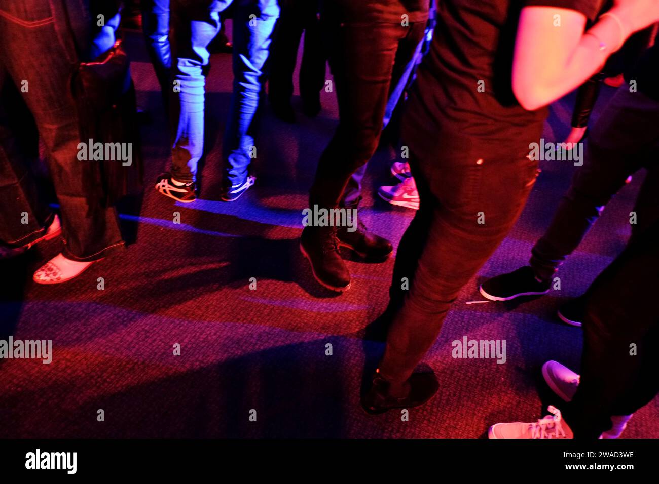 Gambe piedi sneakers e jeans, scarpe, parte inferiore del corpo, persone in conversazione a un evento party, vita notturna di Street Fashion a Sydney Foto Stock