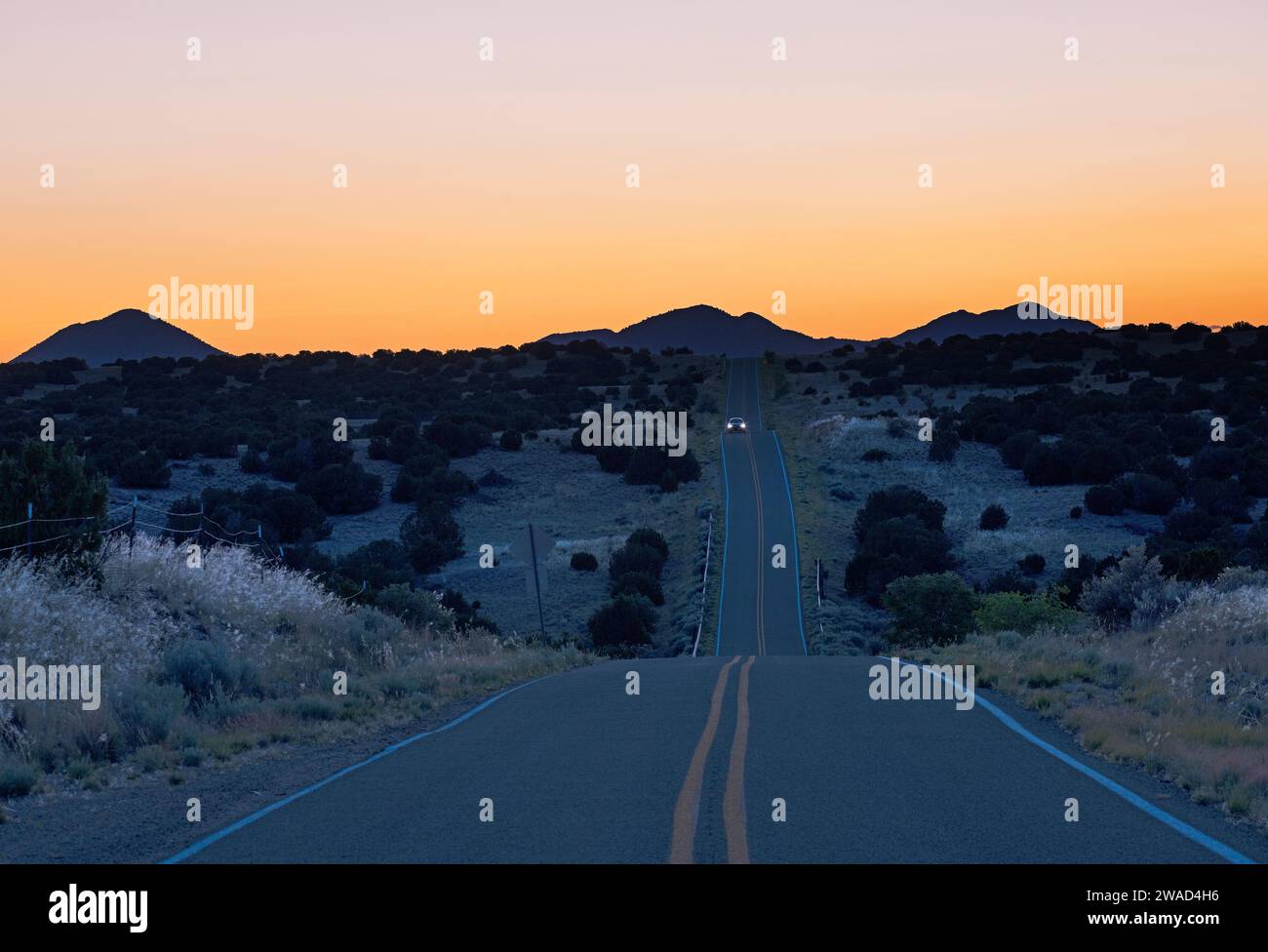 USA, New Mexico, Galisteo, auto su strada nel deserto al crepuscolo Foto Stock