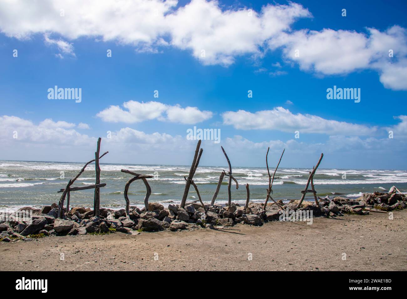 L'insegna di Hokitika Beach in nuova zelanda. Realizzato in legno, l'insegna Hokitika Beach è una delle strutture in legno creative esposte sulla spiaggia. Foto Stock
