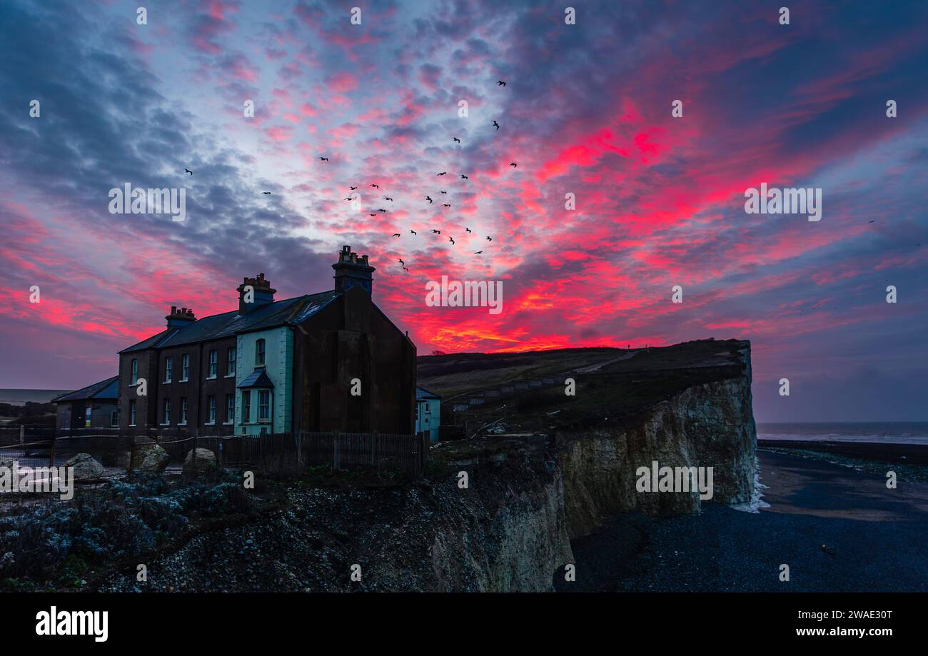 Spettacolare cielo all'alba sopra i precari cottage sul bordo della scogliera di Birling Gap a sud della costa orientale del Sussex, Inghilterra sud-orientale, Regno Unito Foto Stock