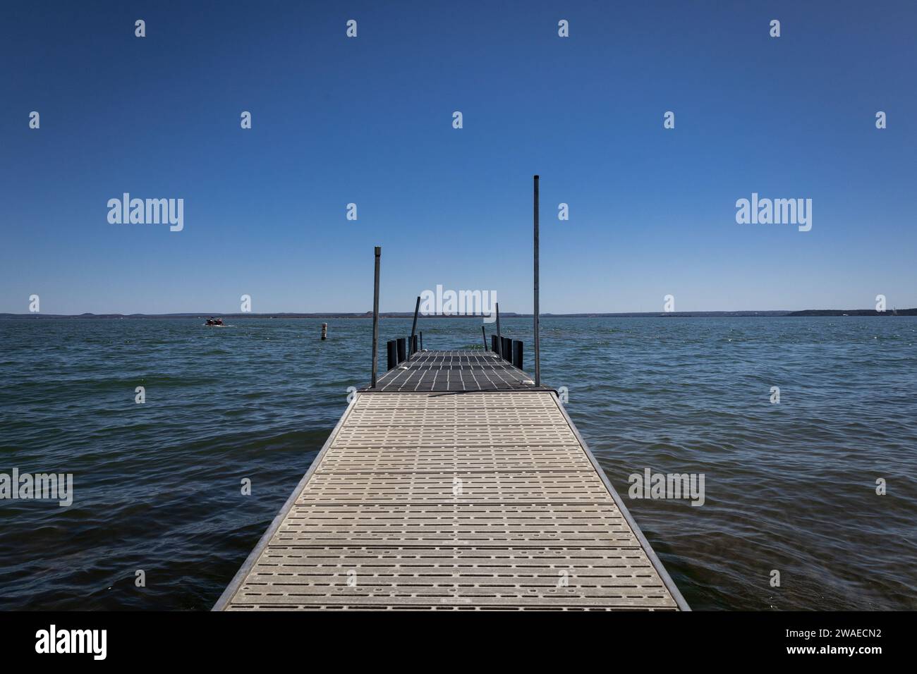 Un molo di attracco per barche in legno in un tranquillo lago del Texas con un cielo blu brillante e senza nuvole sopra la testa Foto Stock