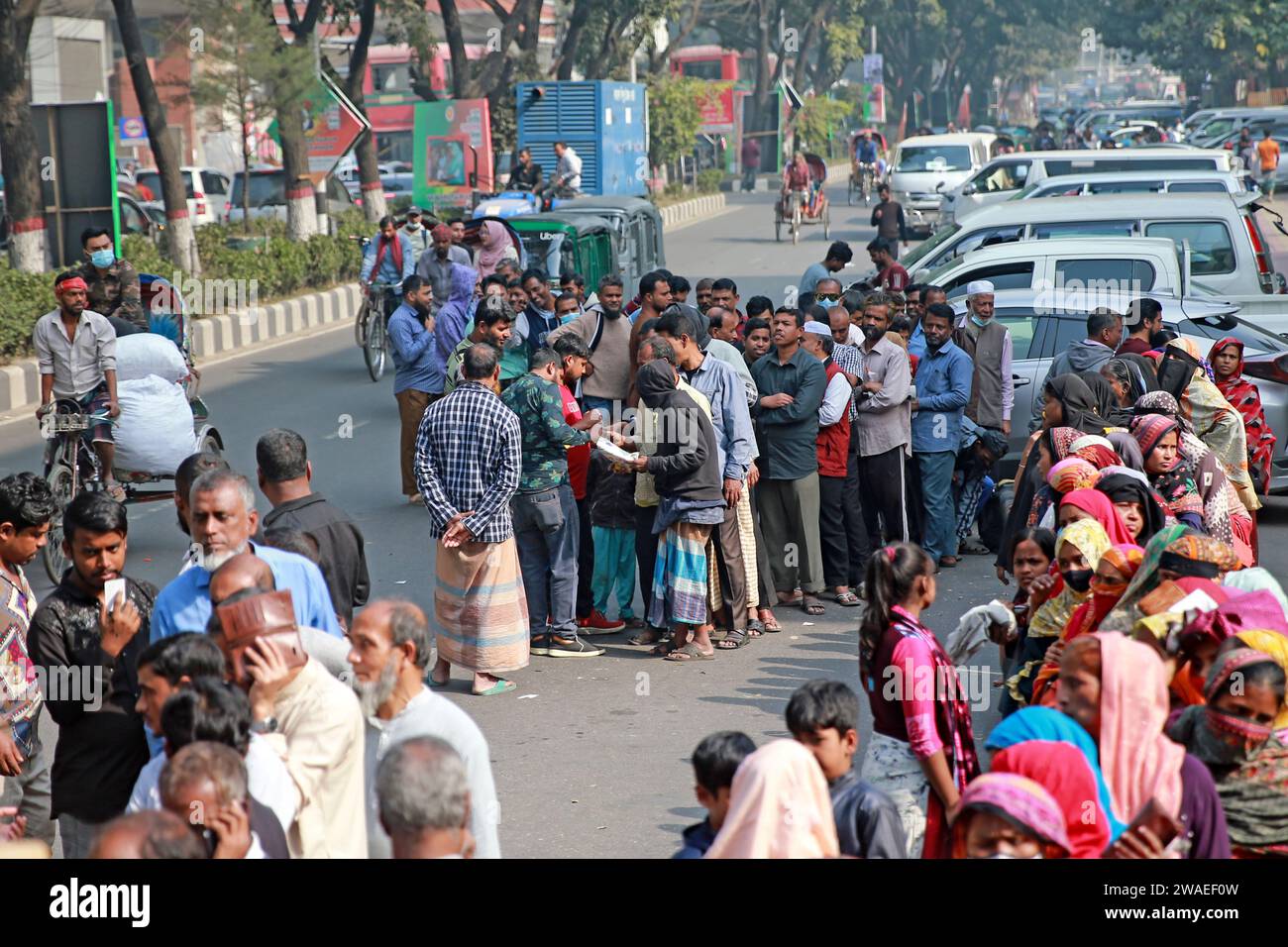 La gente si riunisce intorno a un camion della Trading Corporation of Bangladesh (TCB) parcheggiato a Abdul Gani Road nel pomeriggio della capitale per acquistare gli oggetti essenziali in un fondo Foto Stock