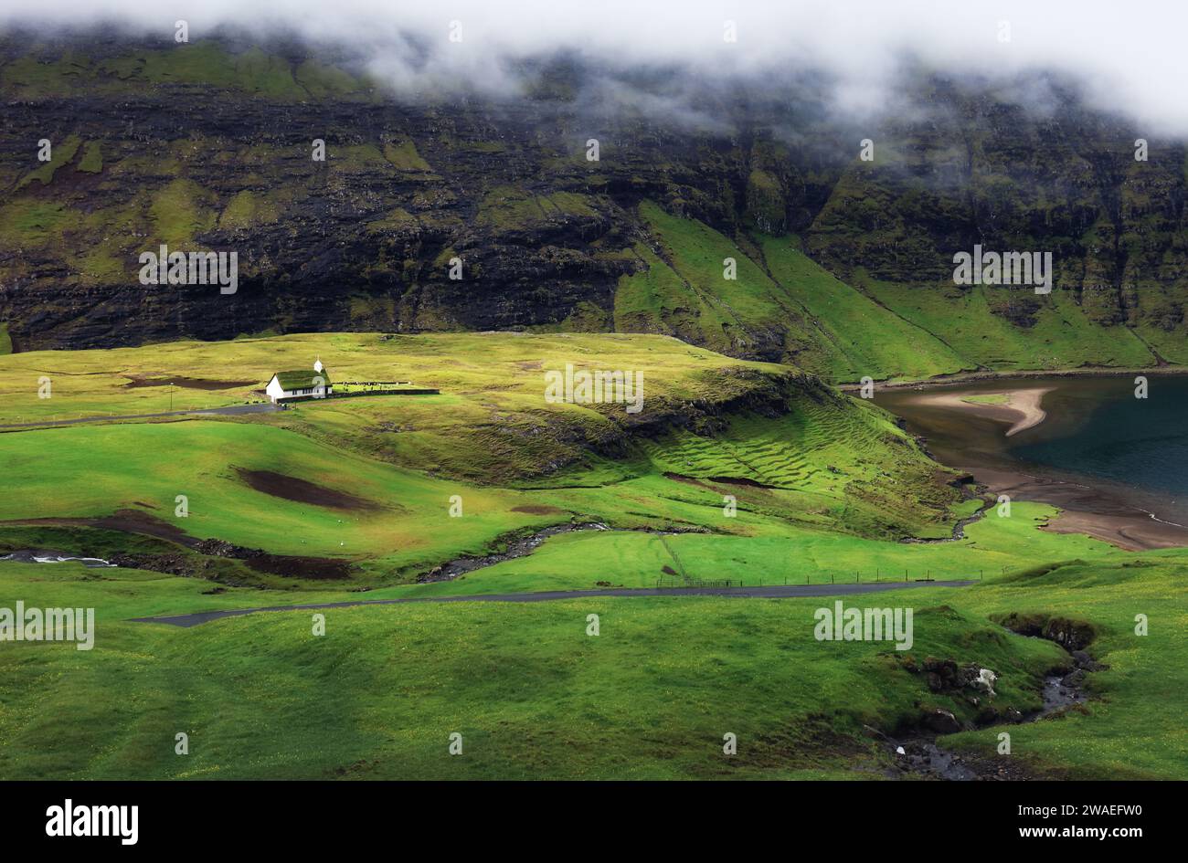 Verde paesaggio montano con vecchie case nelle isole Faroe, Saksun Foto Stock