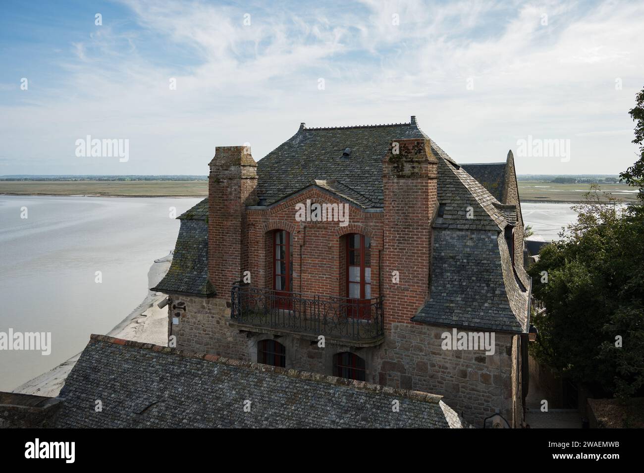 Dettaglio di una delle belle case sul Mont Saint Michele, è possibile vedere il tetto di costruzione classica e il paesaggio e l'orizzonte sullo sfondo Foto Stock