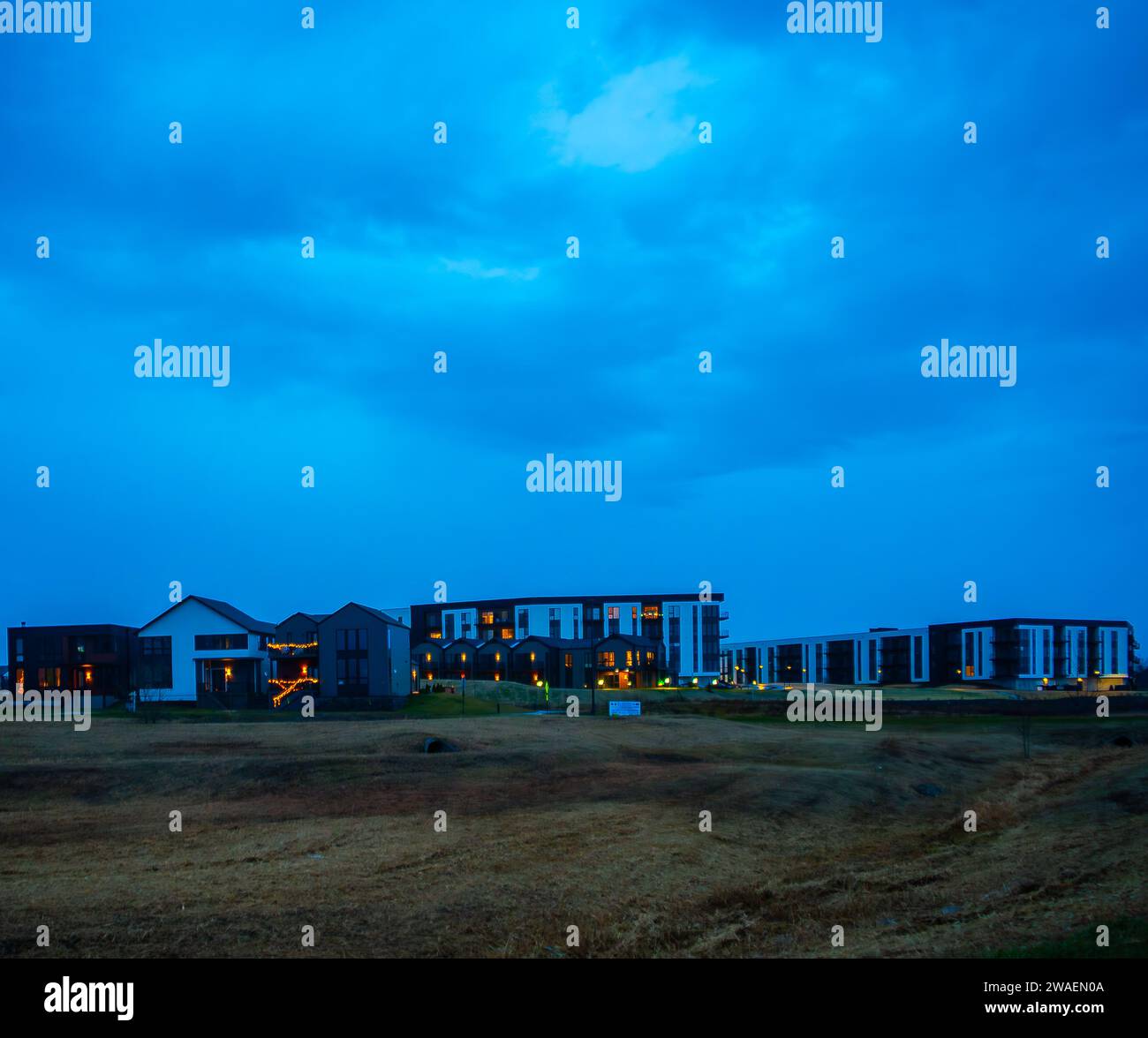 Un paesaggio idilliaco con un campo erboso, con alcuni edifici in lontananza Foto Stock