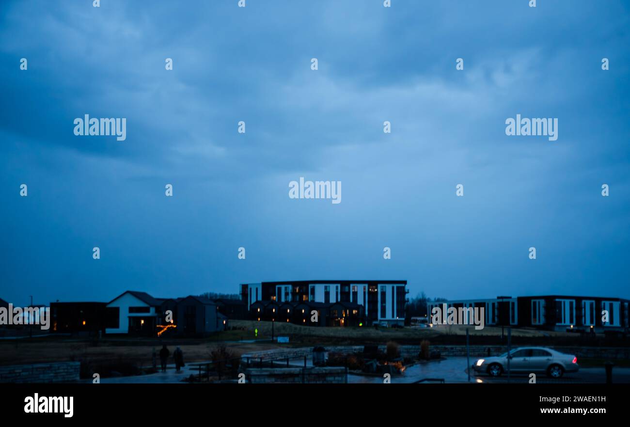 Un paesaggio idilliaco con un campo erboso, con alcuni edifici in lontananza Foto Stock