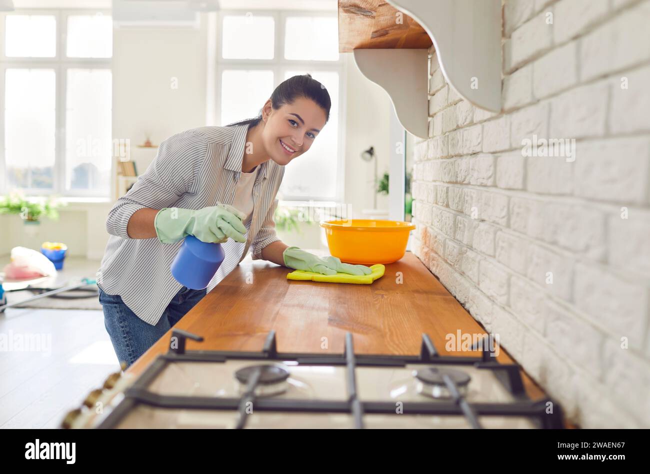 La casalinga sorridente pulisce la polvere in cucina Foto Stock