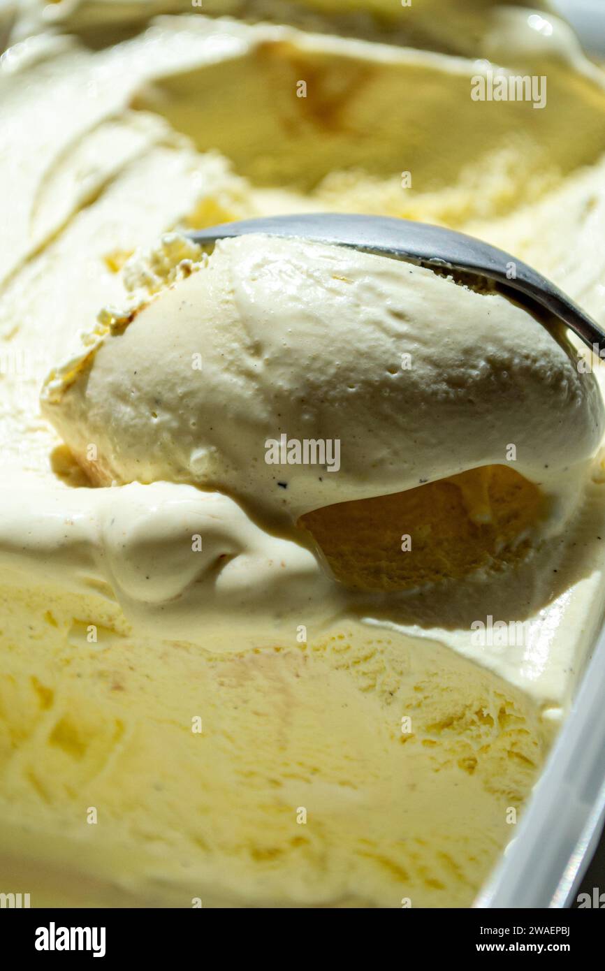 Gelato alla vaniglia estratto da un contenitore con un cucchiaio Foto Stock