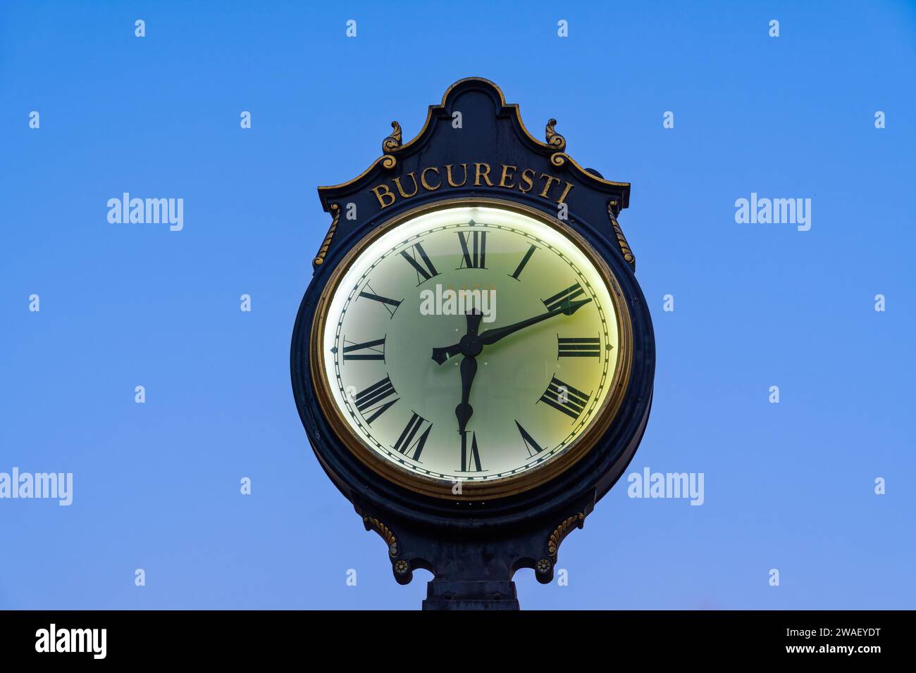 Un grande orologio pubblico tradizionale in Romania che mostra l'ora con la parola Bucuresti in rumeno e l'iscrizione di 1459 anni sotto un cielo limpido in t Foto Stock
