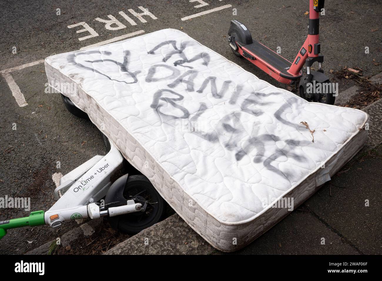 Una matress che è stata scaricata sul marciapiede di Herne Hill ha il nome Daniel Blake spruzzato sulla cima, il 3 gennaio 2024, a Londra, in Inghilterra. "I, Daniel Blake" è un film drammatico britannico del 2016 scritto da Paul Laverty e diretto da Ken Loach che descrive un uomo di mezza età a cui viene negato l'impiego e l'indennità di sostegno nonostante sia stato dichiarato inadatto al lavoro dal suo medico. Più ampiamente, era una critica alle politiche ingiuste del governo conservatore in materia di lavoro e welfare. Foto Stock