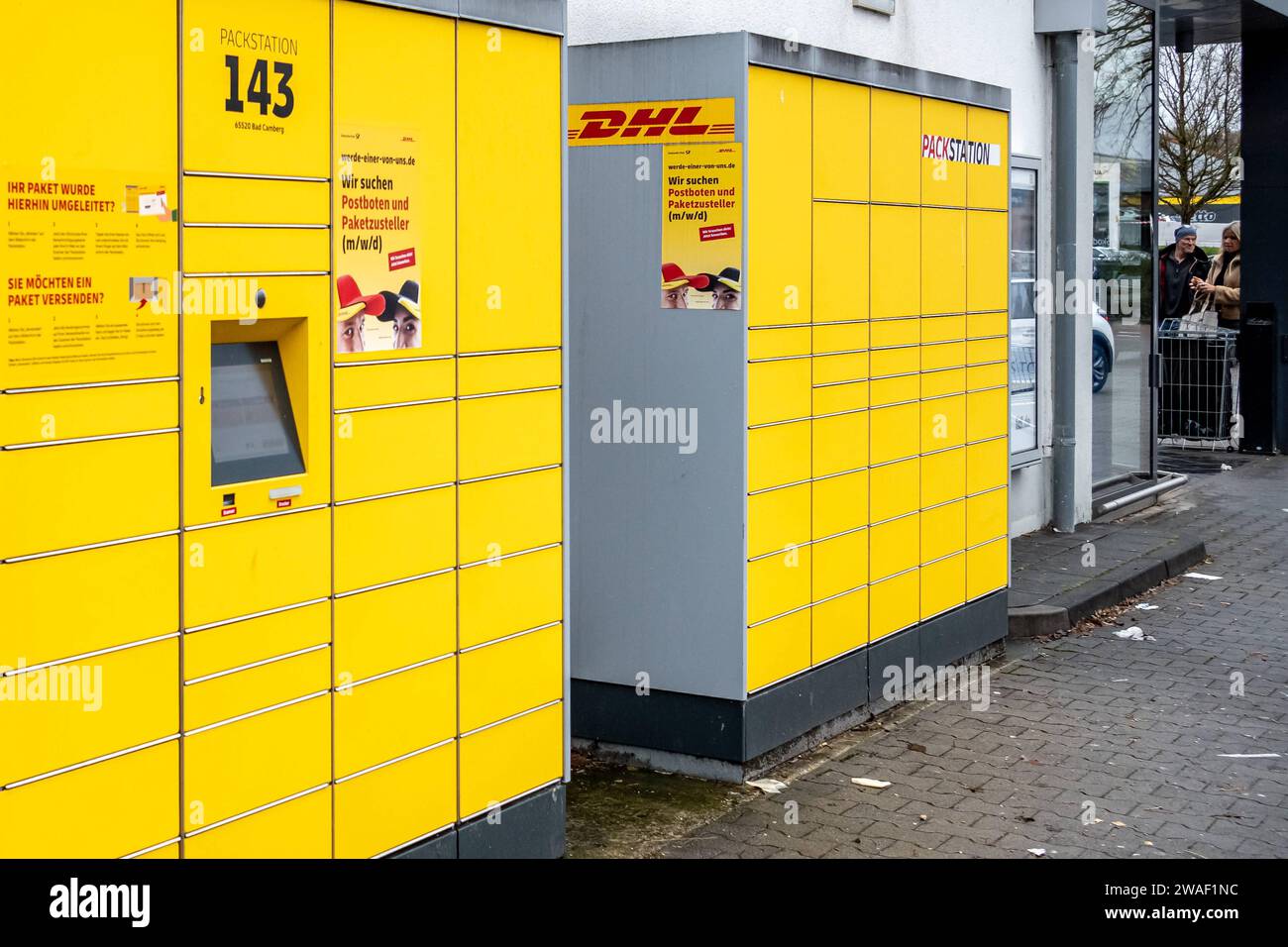 Innovative Paketlogistik - Nutzung der DHL Packstation 04.01.2024, Bad Camberg: Symbolfoto, Illustrationsbild, Symbolbild, Illustrationsfoto Das Bild zeigt eine Frau im Anschnitt, Die mit ihrem smartphone über den touchscreen einer DHL Paketstation interagiert, um ein Paket einzureichen. SIE ist konzentriert auf die digitale Schnittstelle fokussiert, während ihre Hand das Mobiltelefon hält und die entsprechenden Eingaben auf dem Bildschirm der Paketstation tätigt um das Paket einzulegen. Die Packstation, ein Paketautomatensystem von DHL, bietet seit 2001 in über 12,500 Standorten deutschlandwe Foto Stock