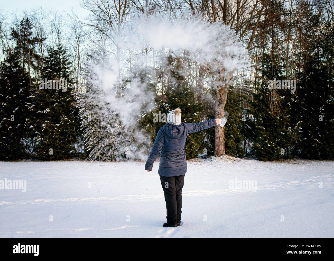 Esperimento di lanciare acqua bollente nell'aria fredda congelante l'acqua evapora rapidamente e si condensa, consentendo la formazione di una nuvola. Scienza divertente. Foto Stock Esperimento di lanciare acqua bollente nell'aria fredda congelante l'acqua evapora rapidamente e si condensa, consentendo la formazione di una nuvola. Scienza divertente. Foto Stock