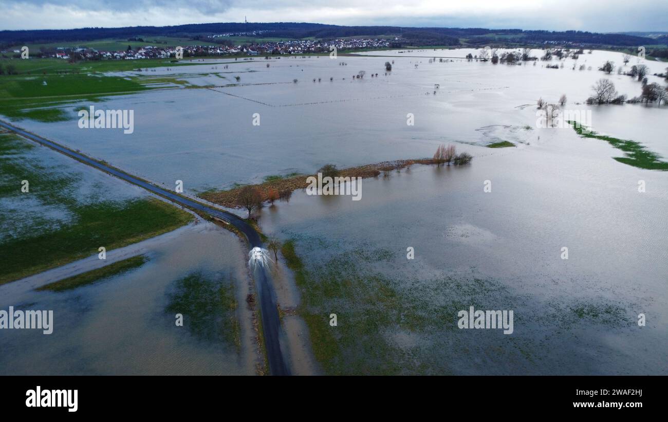 , Assia, Kirchhain, Germania. 4 gennaio 2024. (landkreis Marburg-Biedenkopf): Un'auto guida lungo il bordo del bacino di ritenzione armato dell'Ohm. Non c'è ancora sollievo in vista per le inondazioni in Assia. L'onda di inondazione ha attraversato il corso superiore di molti fiumi dell'Assia e ora si sta rotolando verso le sezioni inferiori. (Foto scattata con un drone). Foto: Nadine Weigel/dpa Foto Stock