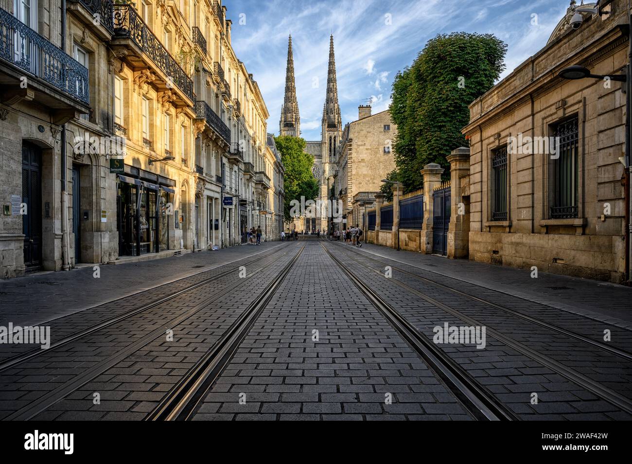 Nel centro di Bordeaux, con i binari del tram, le case storiche e la Cattedrale di St Cattedrale di Andrew alla fine del tramonto. Foto Stock