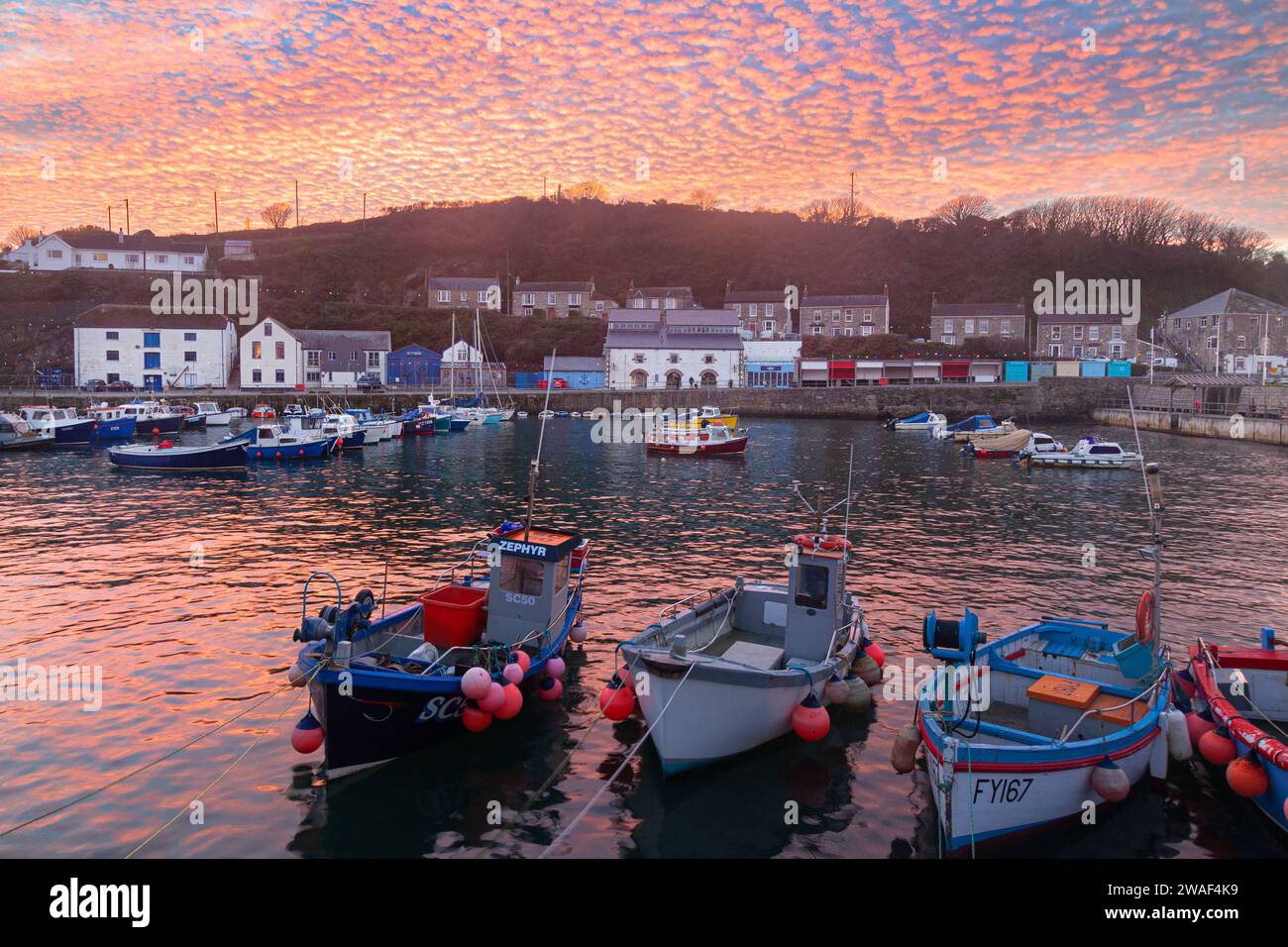 Tramonto di sgombro riflesso nel porto di Porthleven, Cornovaglia, Regno Unito Foto Stock