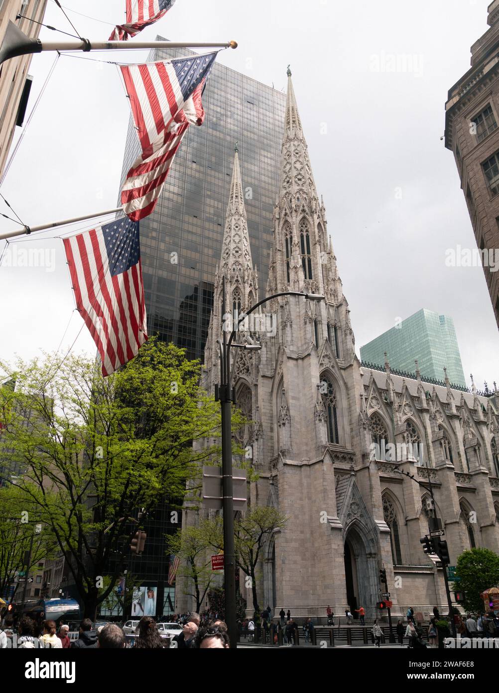 St Patricks Cathedral e Olympic Tower a New York City, New York, Stati Uniti, chiesa gotica, bandiere americane, cielo grigio Foto Stock