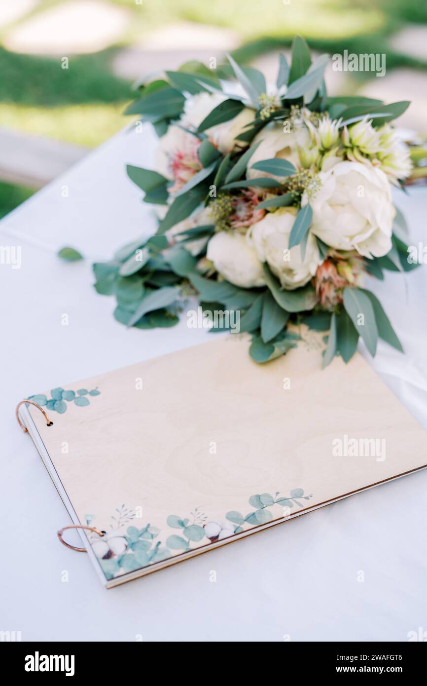 L'album commemorativo degli ospiti si trova sul tavolo accanto al bouquet della sposa Foto Stock