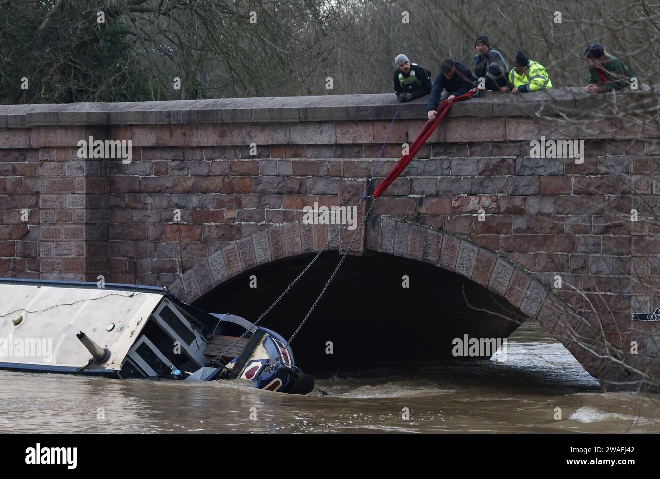 Barrow Upon Soar, Leicestershire, Regno Unito. 4 gennaio 2024. Meteo del Regno Unito. I membri del team di Rivers and Canal Rescue tentano di impedire a una stretta barca di affondare dopo essersi staccati dall'ormeggio durante l'allagamento sul fiume Soar. Alcune parti del Regno Unito sono previste per un altro giorno di condizioni meteorologiche avverse, con centinaia di avvisi e avvisi sulle inondazioni in atto man mano che si prevede una maggiore pioggia. Credit Darren Staples/Alamy Live News. Foto Stock