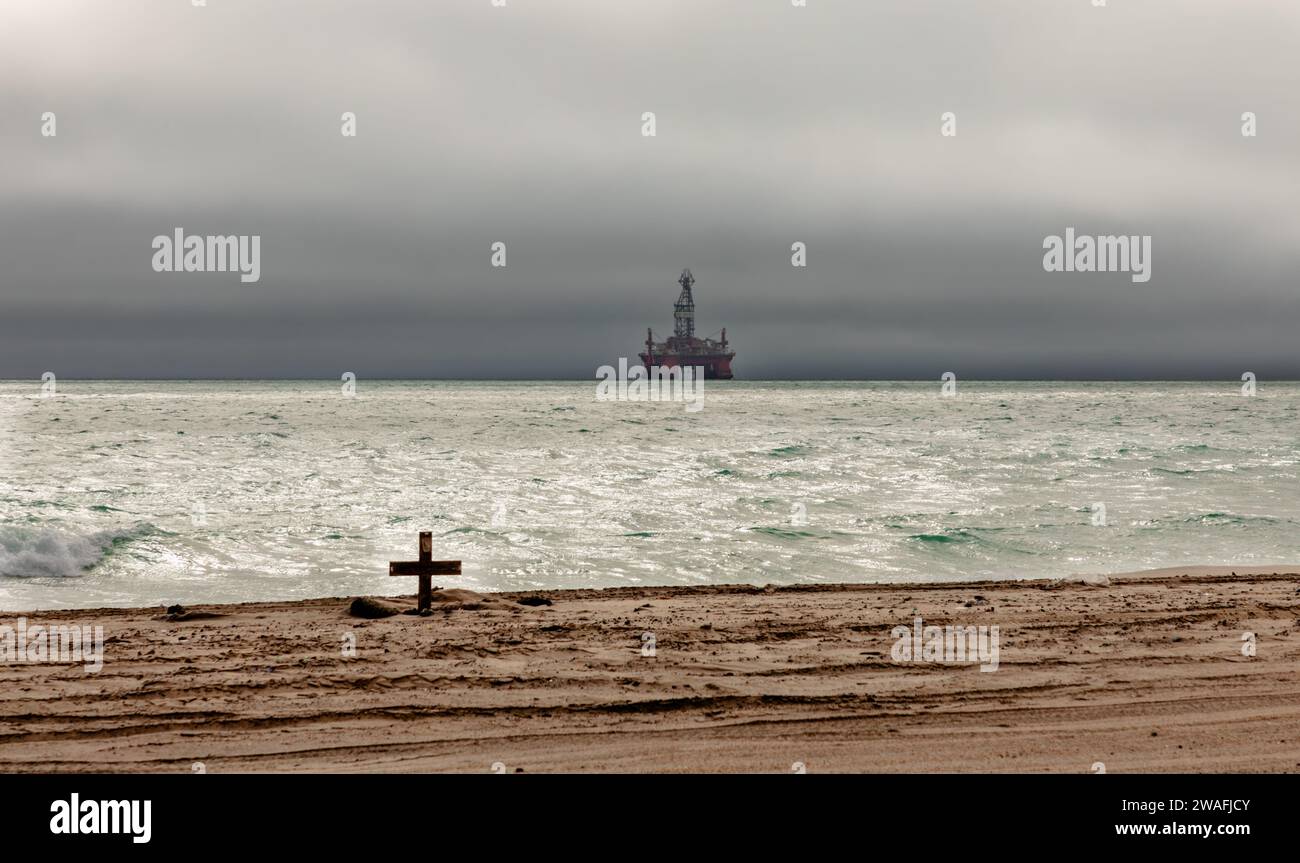 Una piattaforma petrolifera incombe tra cieli minacciosi sull'Oceano Atlantico al largo della costa desertica del Namib in Namibia. Foto Stock