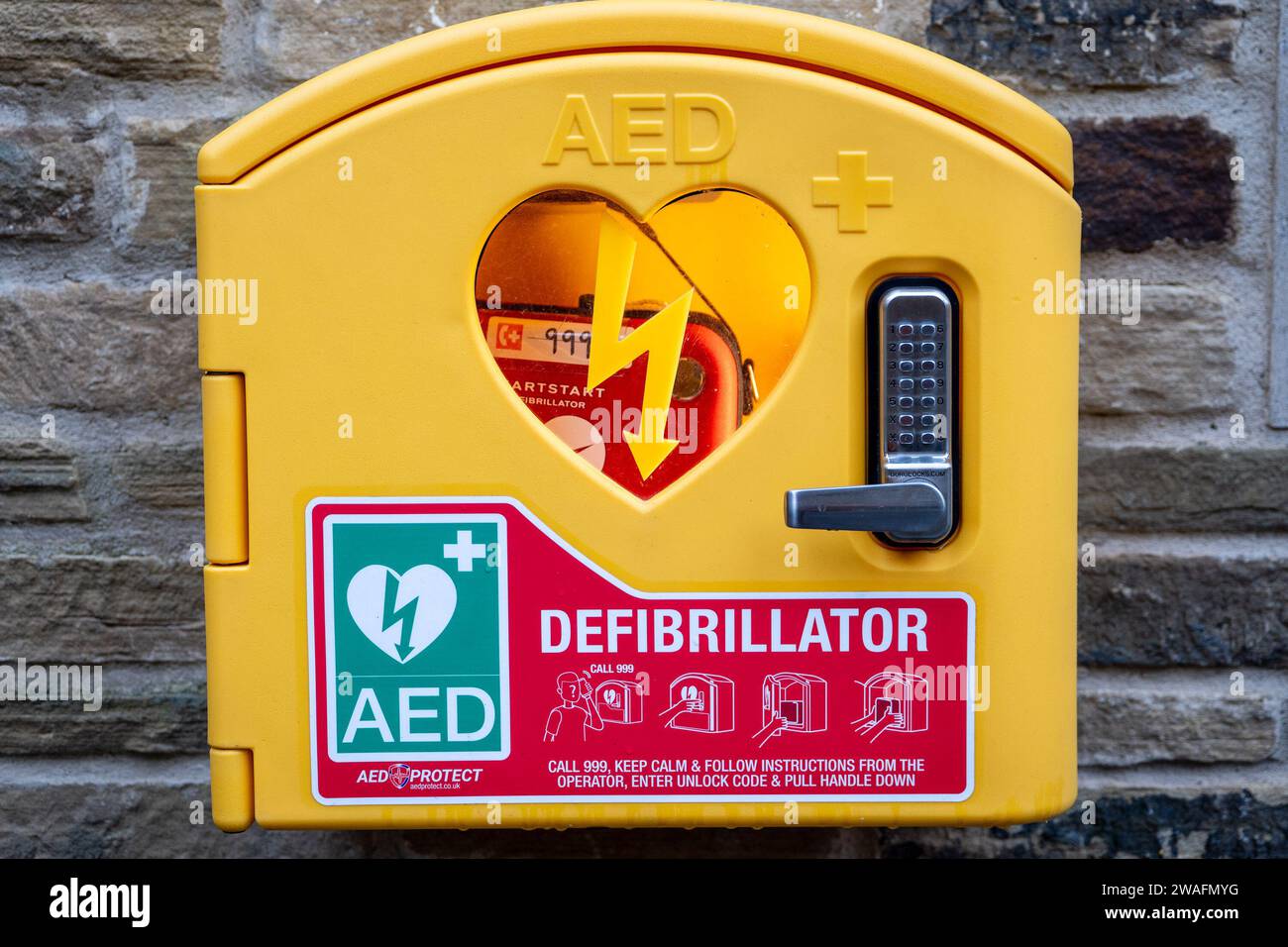 Defibrillatore semiautomatico esterno di emergenza per comunità, montato a parete con un blocco con codice di sicurezza per gli arresti cardiaci nella comunità locale. Foto Stock