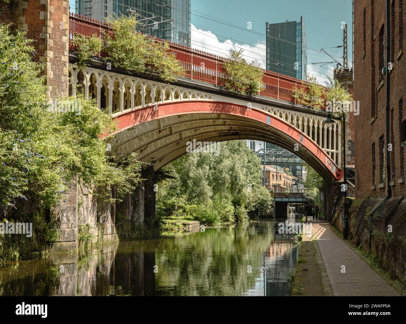 Un ponte ferroviario vittoriano sul canale di Rochdale. Dietro di esso, si innalzano i grattacieli contemporanei che mostrano l'evoluzione della città di Manchester. Foto Stock