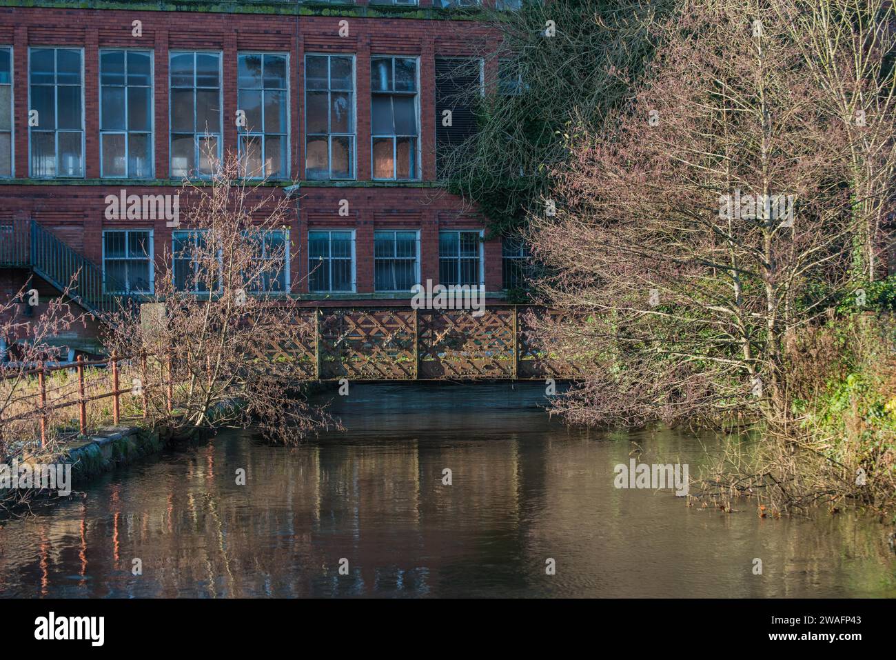 Un vecchio ponte di ferro arrugginito sopra la corsa dei mulini a East Mill a Belper, Derbyshire, Inghilterra Foto Stock
