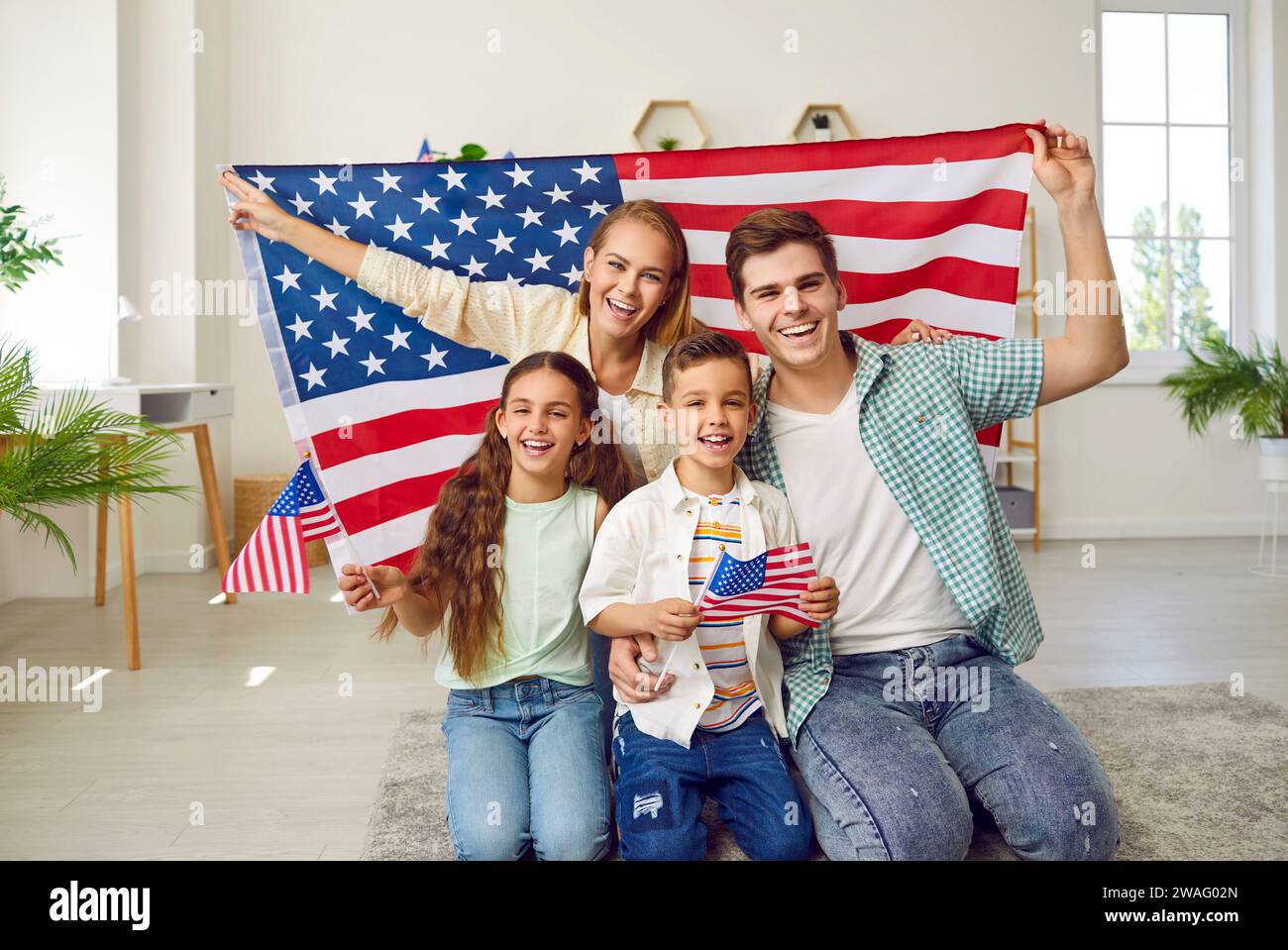 Ritratto di una felice famiglia di patrioti americani che reggono bandiere americane e sorridono Foto Stock