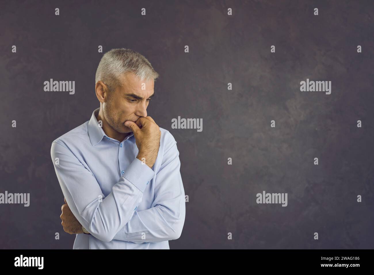 Uomo maturo confuso che pensa a qualcosa di importante in piedi su uno sfondo grigio. Foto Stock