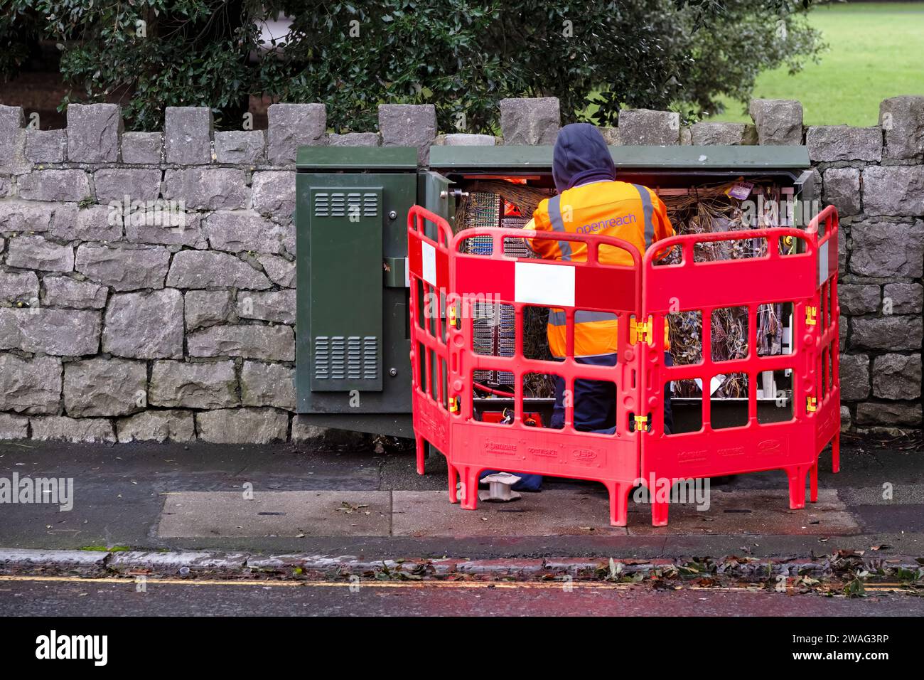 REGNO UNITO. Un ingegnere BT Openreach che lavora su cablaggi e cavi in un armadio BT aperto. L'ingegnere indossa un tabard riflettente Openreach Foto Stock