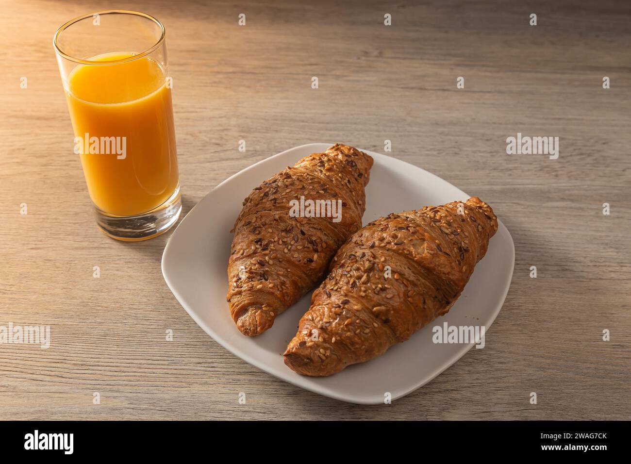Succo d'arancia fresco con croissant su tavola di legno. Foto Stock