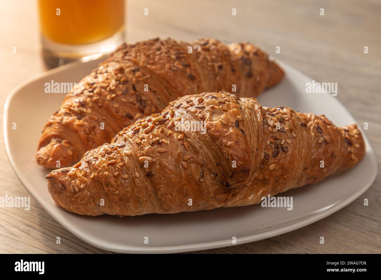 Un bicchiere di succo d'arancia fresco con croissant su un piatto. Primo piano. Foto Stock