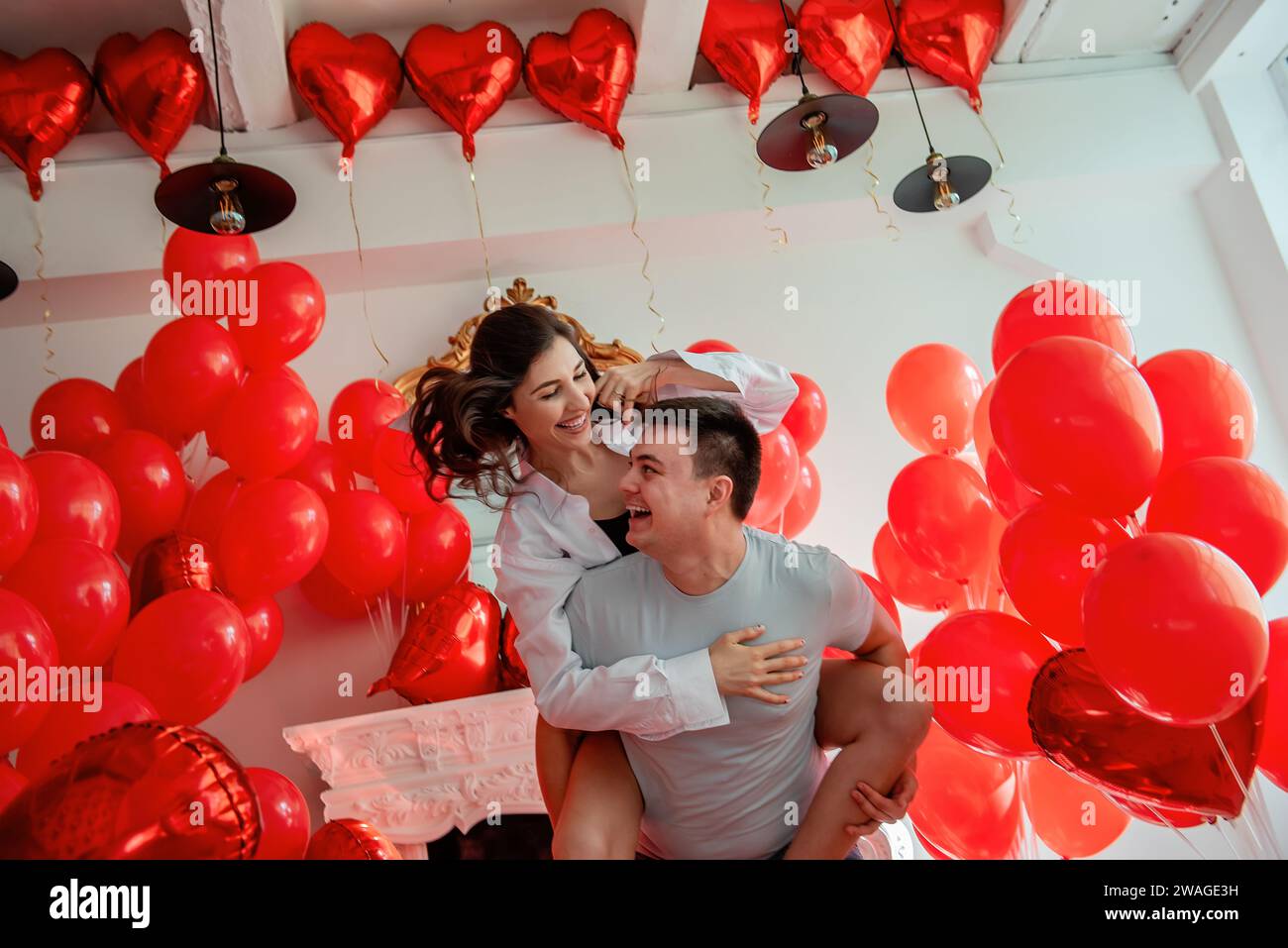 Coppia che ingannano, ridono, guardandosi negli occhi degli altri. Donna seduta sulla schiena di mans. Giorno di San Valentino. Momento divertente e romantico Foto Stock