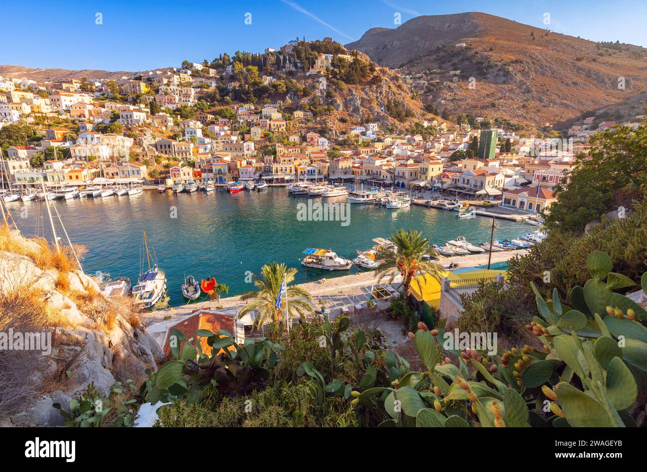 Vista delle case tradizionali colorate e delle barche da pesca nel villaggio di pescatori di Symi in una giornata di sole. Grecia. Dodecaneso. Foto Stock