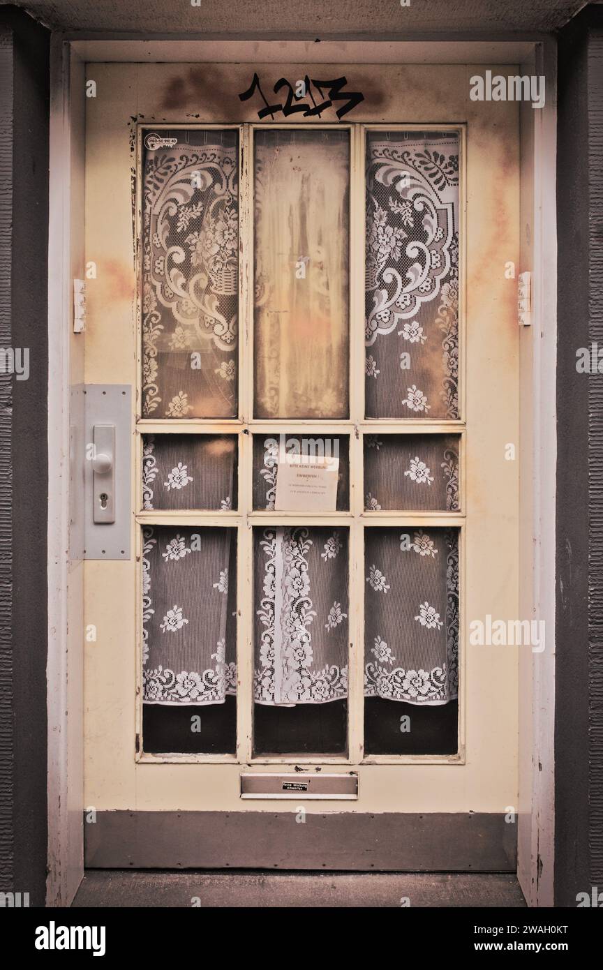 Ripresa verticale di una vecchia porta d'ingresso bruciata ad Essen, Germania, con eleganti tende visibili dietro di essa Foto Stock