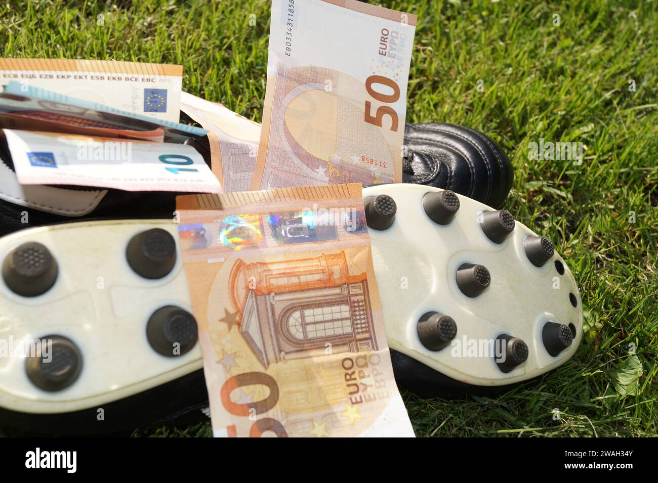Scarpa da calcio con euro su un campo da calcio, immagine simbolica del calcio professionistico Foto Stock
