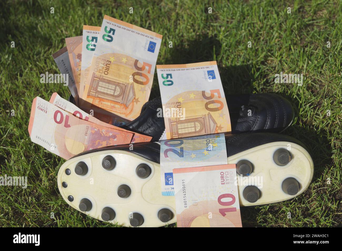 Scarpa da calcio con euro su un campo da calcio, immagine simbolica del calcio professionistico Foto Stock