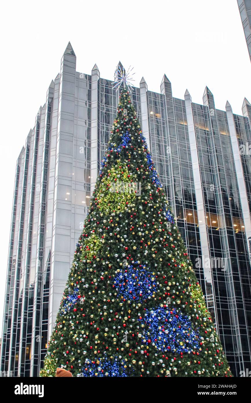 L'albero di Natale nel centro della pista di pattinaggio su ghiaccio PPG Arena è illuminato con il grattacielo Pittsburgh Plate Glass Skyscraper sullo sfondo Foto Stock