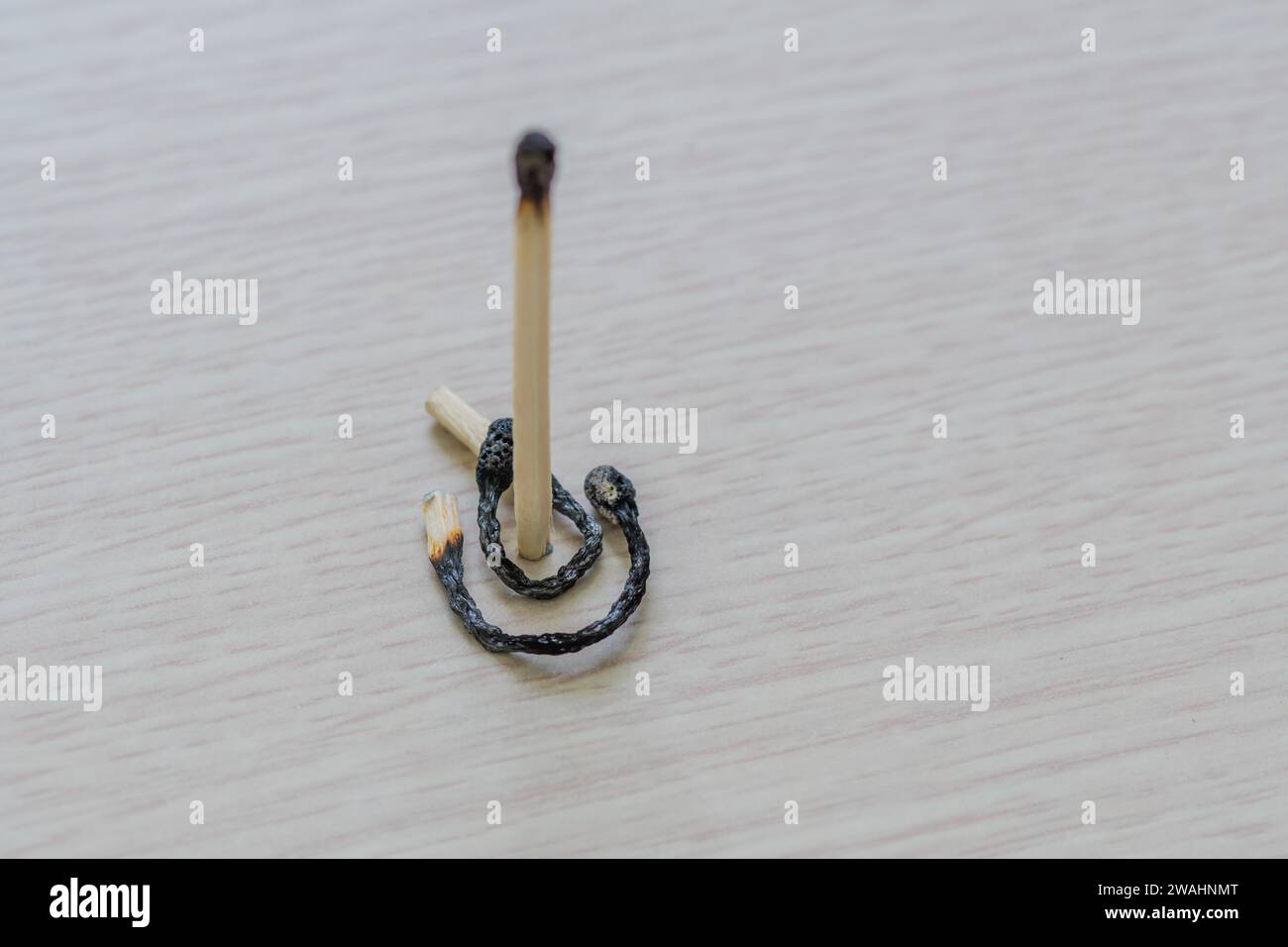 Resti di fiammiferi bruciati che hanno assunto forme strane su uno sfondo a grana di legno Foto Stock