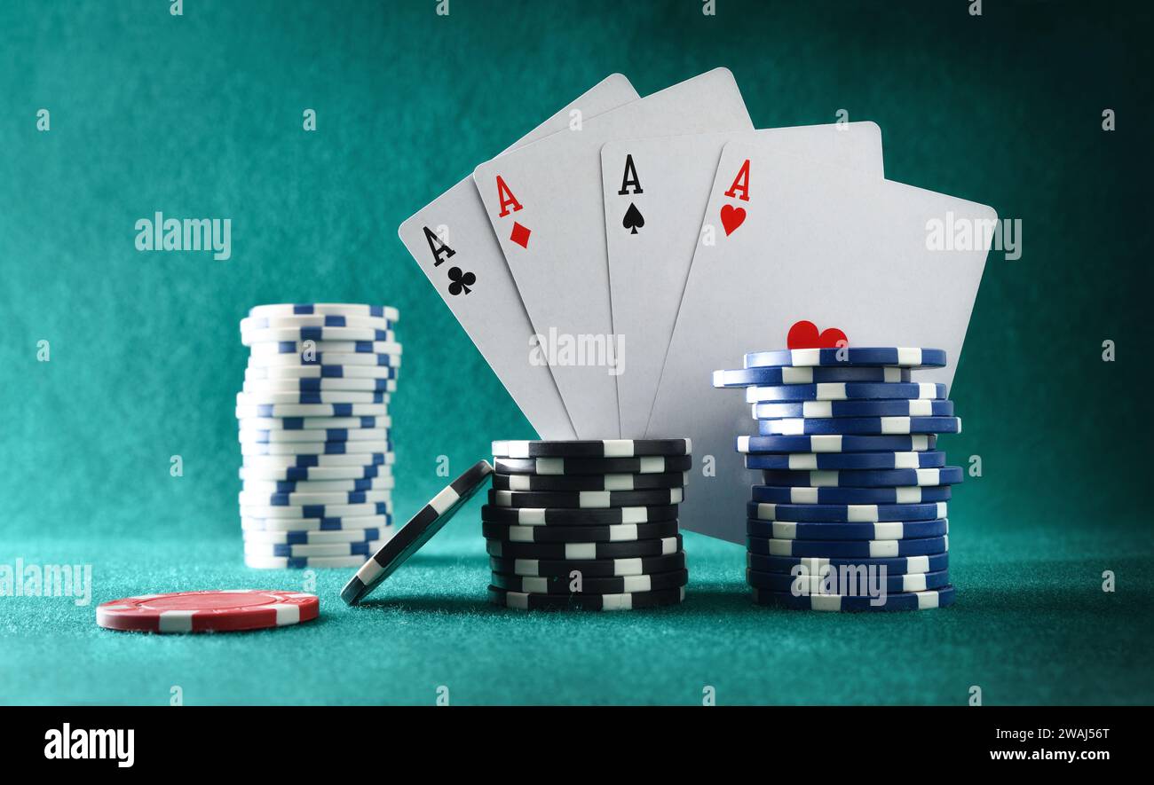 Carte da gioco che mostrano quattro assi e gettoni per le scommesse su un tavolo da gioco in feltro verde e sullo stesso sfondo. Vista frontale. Foto Stock