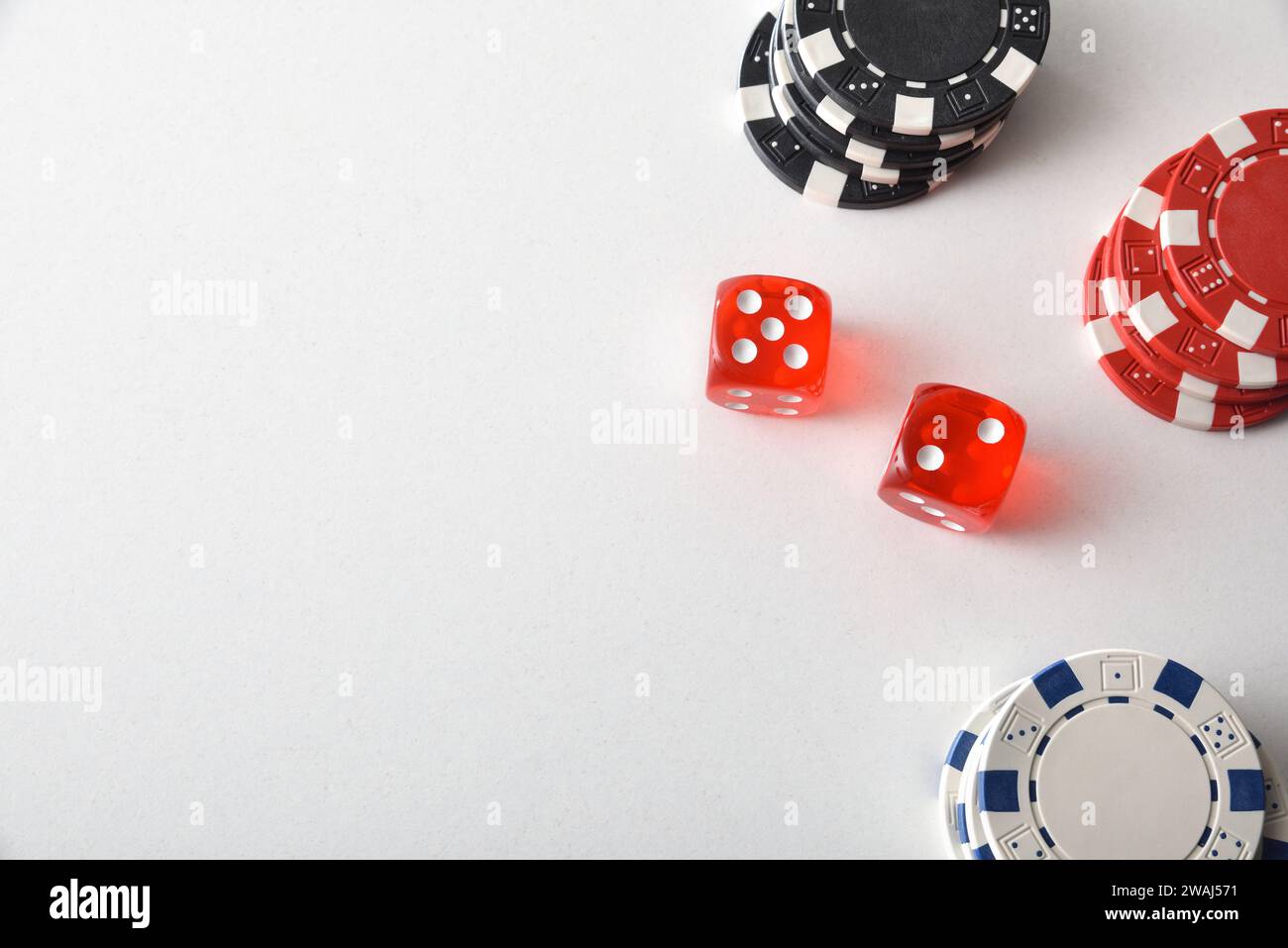 Sfondo di gioco dei dadi del casinò con una pila di patatine colorate per le scommesse e due dadi rossi intorno al tavolo bianco. Vista dall'alto. Foto Stock