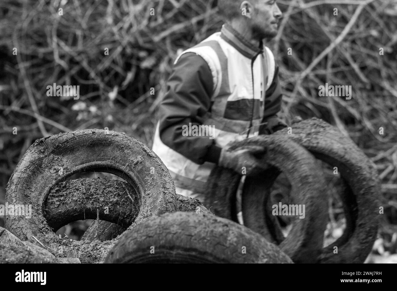 Lavoratore che pulisce pneumatici e letame scaricati dopo la protesta degli agricoltori, Quai Eugène Cavaignac, Cahors, dipartimento Lot, Francia Foto Stock