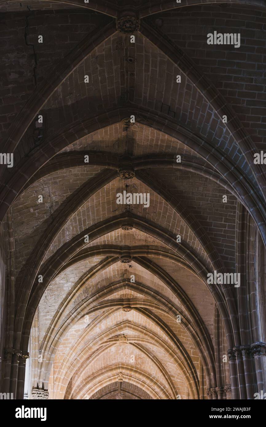 Foto verticale degli archi gotici a volta all'interno di una cattedrale di Bayonne che mostra la maestria architettonica con un gioco di luci e ombre Foto Stock
