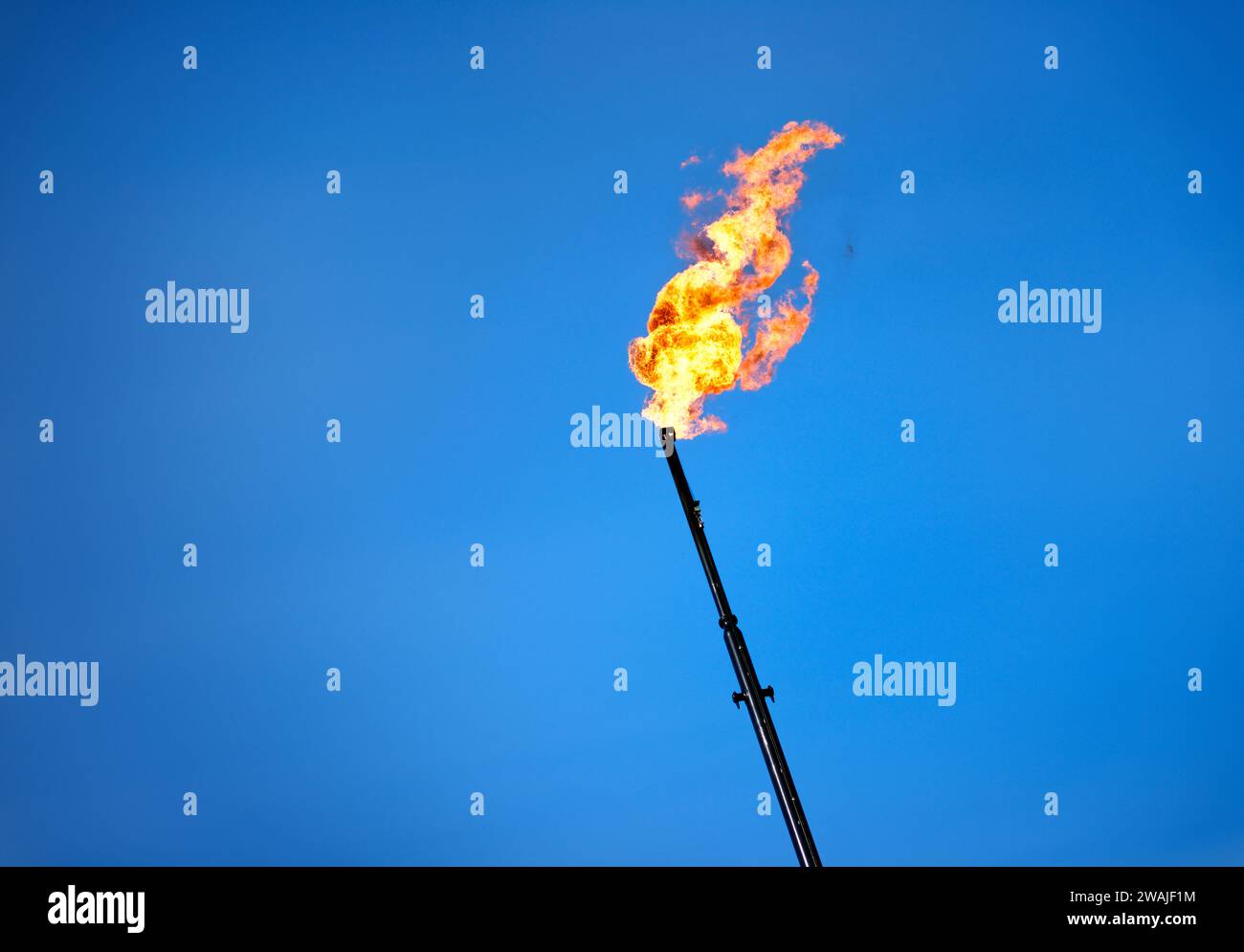 Una pila di combustione in fiamme in una raffineria di petrolio che rilascia gas combusti nell'atmosfera Foto Stock