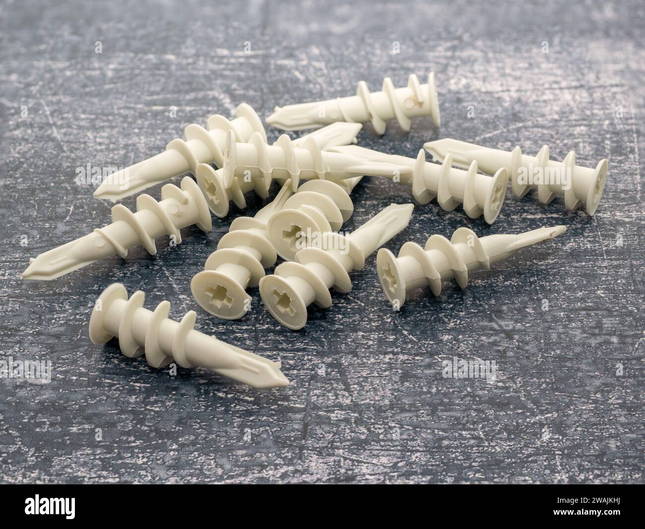 Tappi di ancoraggio per pareti autoforanti bianchi isolati su uno sfondo di cemento Foto Stock
