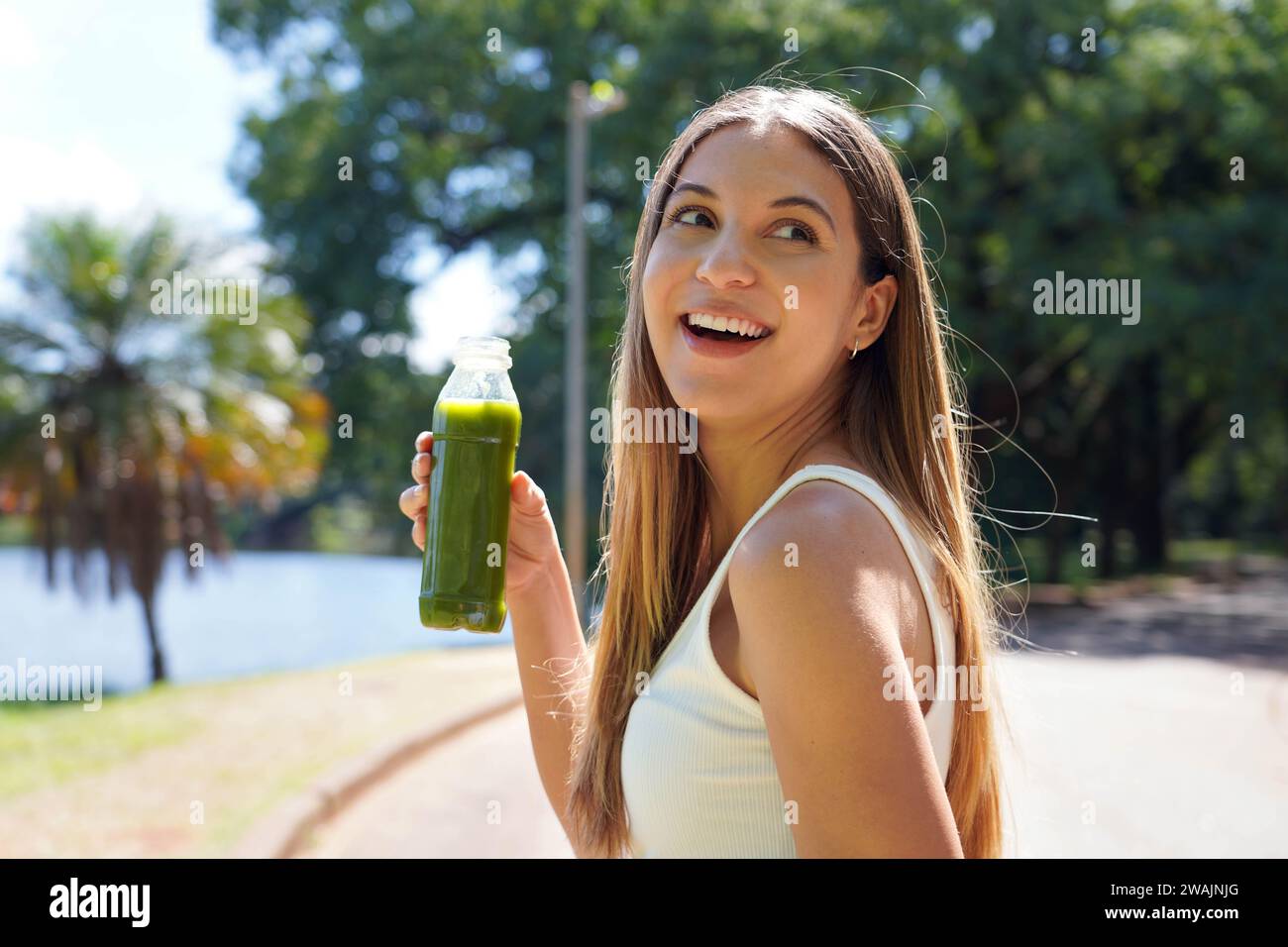 Attraente ragazza sportiva brasiliana che tiene all'aperto Green Smoothie Detox Juice Foto Stock