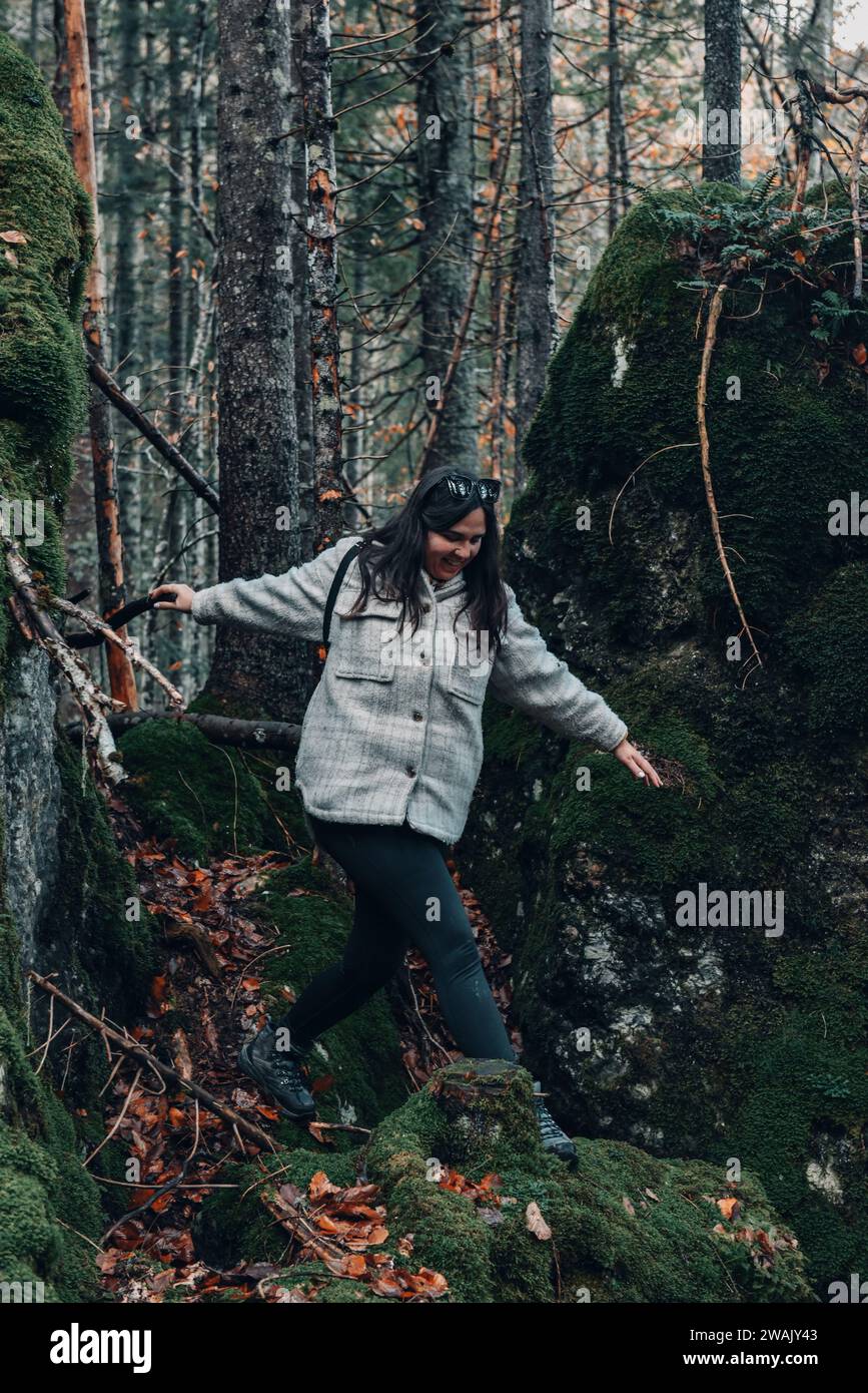 Una giovane donna caucasica con un cappotto che cammina in una foresta di muschi Foto Stock