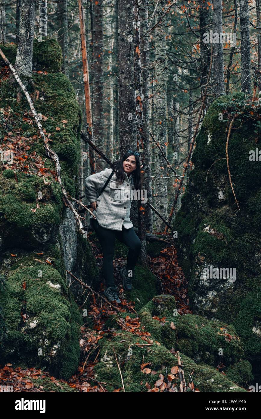 Una giovane donna caucasica con un cappotto che cammina in una foresta di muschi Foto Stock