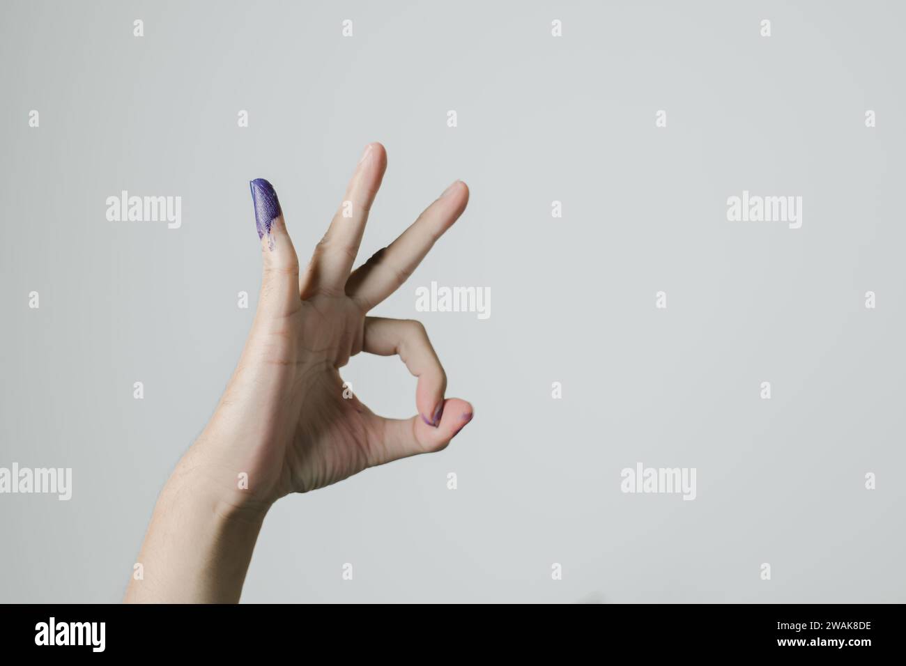 Una mano con un gesto OK e inchiostro viola applicato sul mignolo dopo le elezioni presidenziali indonesiane o pemilu Foto Stock